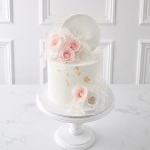 Tort elegant alb cu flori roz, decor dantelat și accente aurii