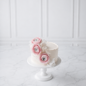 Tort floral elegant cu ranunculus roz și decor delicat